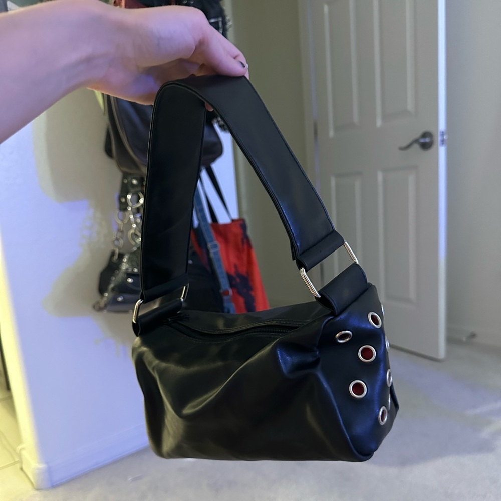 Leather shoulder bag with red interior grommets